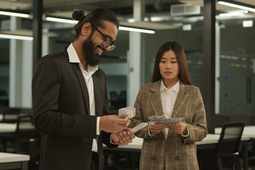 Arabian happy businessman with many money man count banknotes and sad Asian businesswoman woman with little finance salary in office money inequality equal pay discrimination cash business colleagues. High quality 4k footage